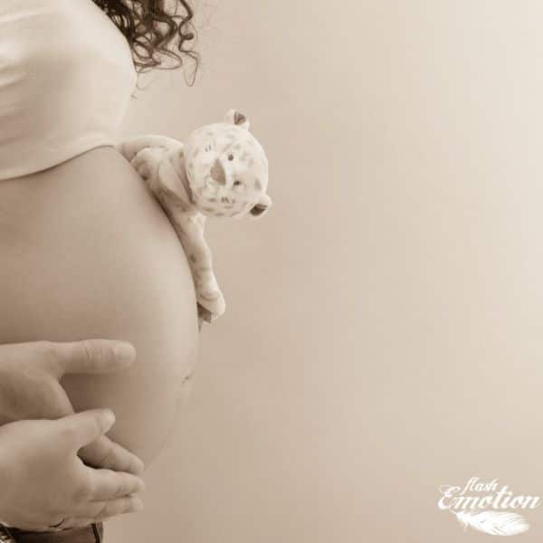Photo en plan rapproché d'une femme enceinte avec des mains sur le côté de son ventre et une peluche dessus